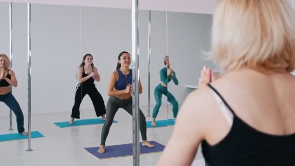 Mujeres jóvenes calentando sus cuerpos frente al espejo antes de bailar - sentadas en cuclillas — Vídeo de stock