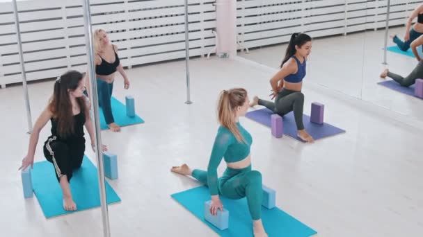 Parlak stüdyoda, elleri tuğlalı yoga minderleri üzerinde spor yapan genç kadınlar. — Stok video