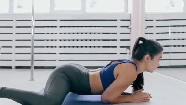 Fiatal nők edzés a jóga szőnyegen - nyújtózkodás a béka pózban — Stock videók