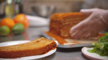 Chef cutting a big piece out of honey cake and putting in on the separate plate