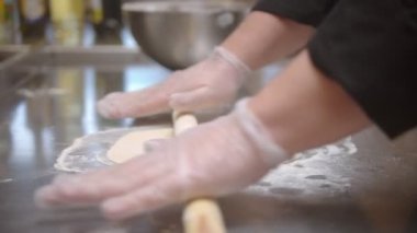 Restaurant kitchen - making a dough - flatten the dough with a rolling pin