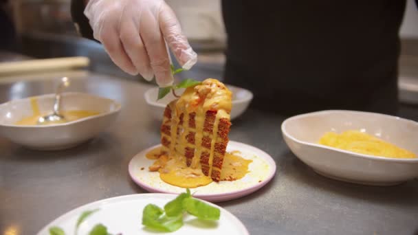 Шеф-повар украшает кусок сладкого торта мятой — стоковое видео
