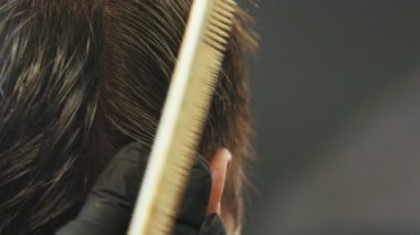Barber cutting clients wet hair with a thinning scissors