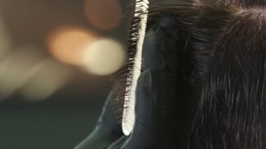 Barber in black gloves cutting clients wet hair with a thinning scissors
