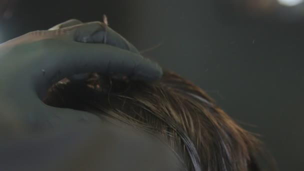 Парикмахер в перчатках расчесывает клиентов мокрыми волосами на затылке — стоковое видео