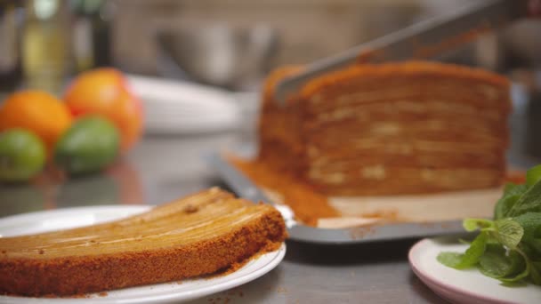 요리사가 꿀 케이크에서 큰 조각을 잘라 내는 모습 — 비디오
