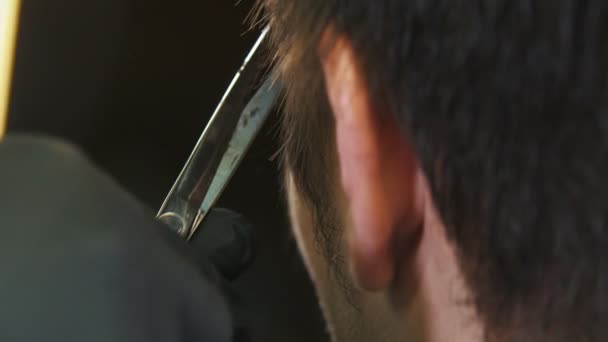 Barber in black gloves cutting clients wet hair on the temples with a scissors — 图库视频影像