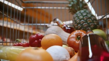 grocery basket - man is putting bread in a trolley full of fruits, vegetables and drinks