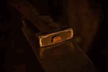 Parlayan çekiç, siyah ışıkta örsün üzerinde yatıyor.