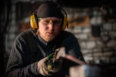 Demirci makinesiyle sıcak metalden bir ayrıntı çıkaran bir işçi.