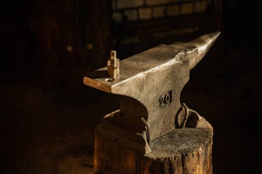 Atölyede güneş altında örsün üstünde bir çekiç.