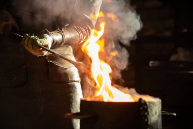 Demirci bir kova suya yanan bir şey koydu.