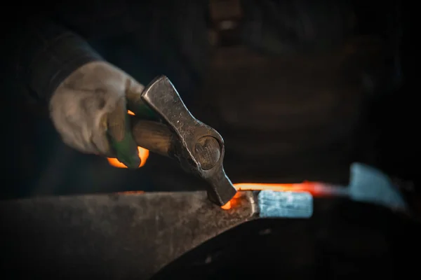 Demirci, çekici kullanarak sıcak metalden bıçak dövüyor. Bıçağı forseps içinde tutuyor. — Stok fotoğraf