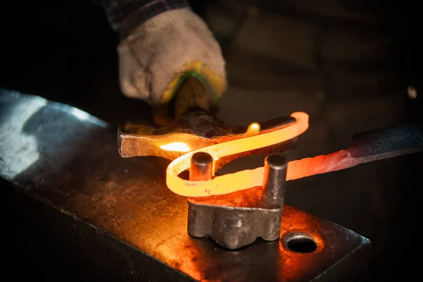 Un fabbro uomo che fa una maniglia unica per il coltello piegando il metallo — Foto Stock