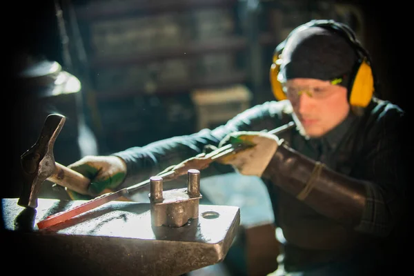 Un forgeron homme dans des lunettes de protection faisant un objet — Photo