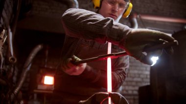 Demirci sıcak bir metal parçasını büküyor.