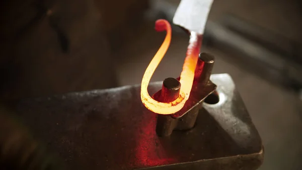 Ferreiro dobrando um pedaço de metal quente em uma alça de faca — Fotografia de Stock