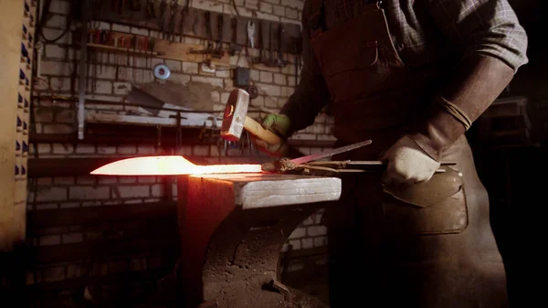 Un uomo fabbro forgiare una lama di coltello caldo con un martello — Foto Stock