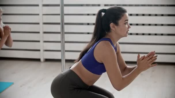 Jovem mulher treinador mostrando agachamento enquanto o treinamento de fitness — Vídeo de Stock