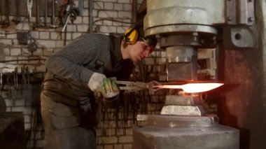 A man blacksmith forming a knife using an industrial pressure machine