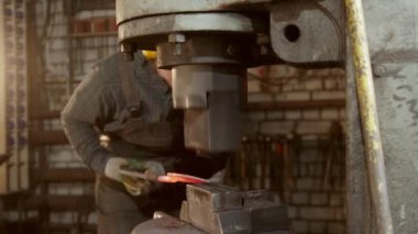 Demirci, endüstriyel basınç makinesi kullanarak bir bıçak oluşturuyor.