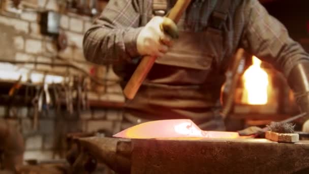 Trabajador herrero forjando un cuchillo del metal caliente en el taller — Vídeos de Stock