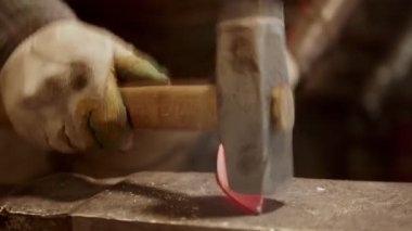 A man working blacksmith making a knife of metal