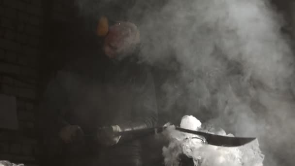 Trabajador herrero enfriamiento cuchillo de metal caliente - vapor sale de la hoja — Vídeo de stock