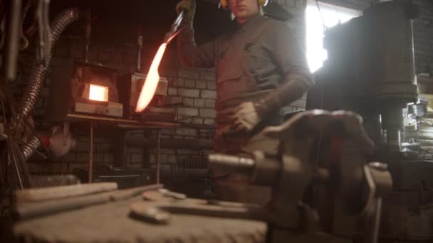 A man blacksmith forging a knife - putting the sample between the clamps — Stock videók