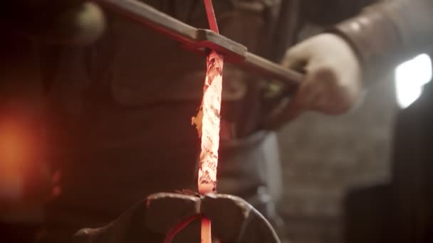 Ein Kunstschmied dreht ein Stück Metall — Stockvideo