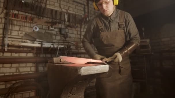Кузнец, ковавший нож с выкрученной ручкой - кладет его в печь для лучшего нагрева — стоковое видео