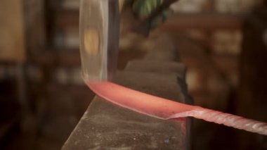 A man blacksmith hitting a hot knife with a hammer