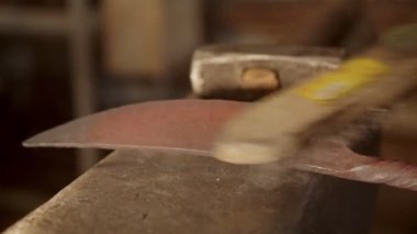 Blacksmith brushing off the leftovers from the knife blade - sparkles comes off the blade