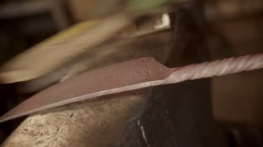 Blacksmith brushing off the leftovers from the knife blade sample