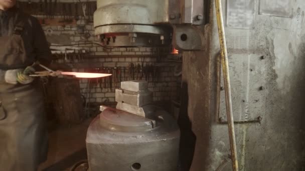 A man blacksmith putting a knife under the pressure of special machine — Stockvideo
