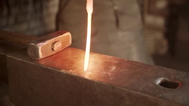 Человек кузнец кладет горячий образец ножа на наковальню — стоковое видео
