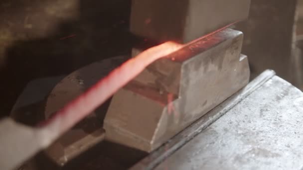 ブラックスミスは機械の圧力下で長い金属片を作る — ストック動画
