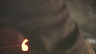 Blacksmith bending a longer piece of hot metal