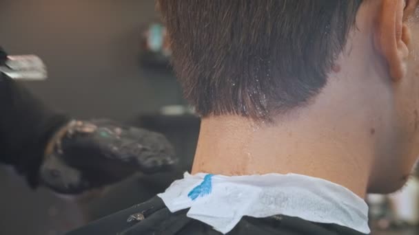 Um barbeiro fazendo toques de acabamento usando lâmina de perigo nas bordas do cabelo — Vídeo de Stock