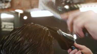 Berber müşterisine saç kurutma makinesi ve fırçayla ıslak saç stili yapıyor.