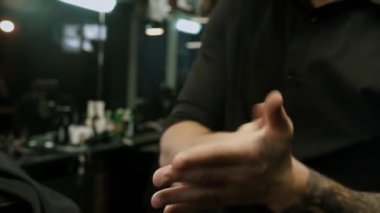 Maskeli berber müşterisinin saçını jöle kullanarak şekillendiriyor.