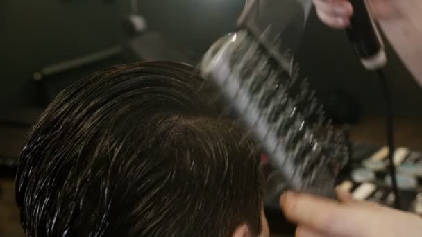 Peluquero con máscara negra peinando el cabello de su cliente con secador de pelo y cepillo de peine — Vídeo de stock