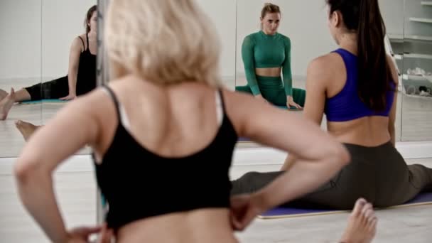 Группа женщин, сидящих в ногах, расщепляется перед зеркалом и делает упражнения — стоковое видео
