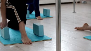 Ellerinin altındaki tuğlalara yaslanmış yoga minderleri üzerinde egzersiz yapıyor.