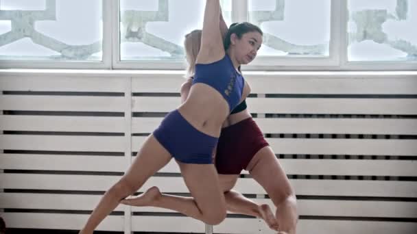 Жінки, які тренуються танцювальними полюсами в студії - дві жінки обертаються на одному полюсі — стокове відео