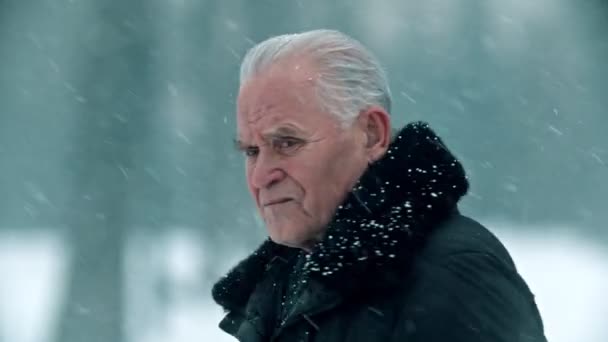 Старый дед - седой дед с лысой головой стоит на улице в снегопаде — стоковое видео