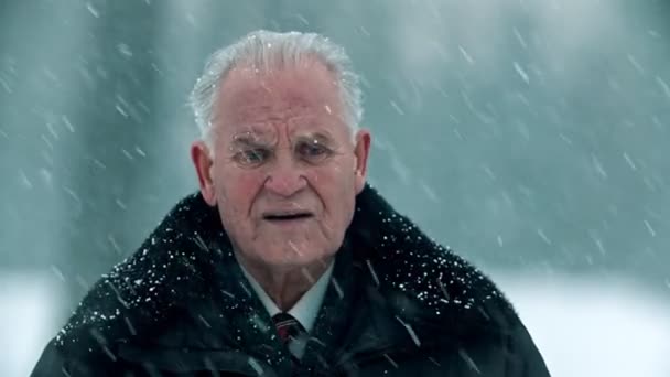 Elderly grandfather - gray-haired sad grandfather is standing outside in snowfall — Stockvideo