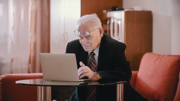 Elderly grandfather - old grandfather is putting on glasses and keeps typing