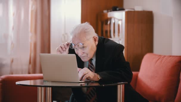 Elderly grandfather - old grandfather is putting on glasses and keeps typing — Stock video