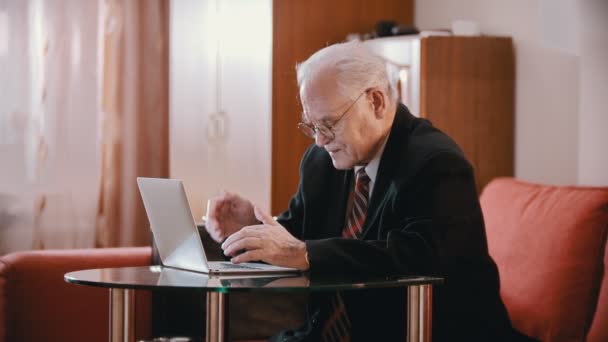 Anciano abuelo - abuelo está escribiendo lentamente algo en la computadora en la habitación — Vídeos de Stock